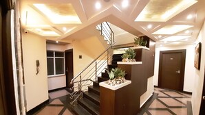 A modern hotel lobby with a central staircase, a reception desk, and a door marked with the number 2. - Liza Regency (Chennai)