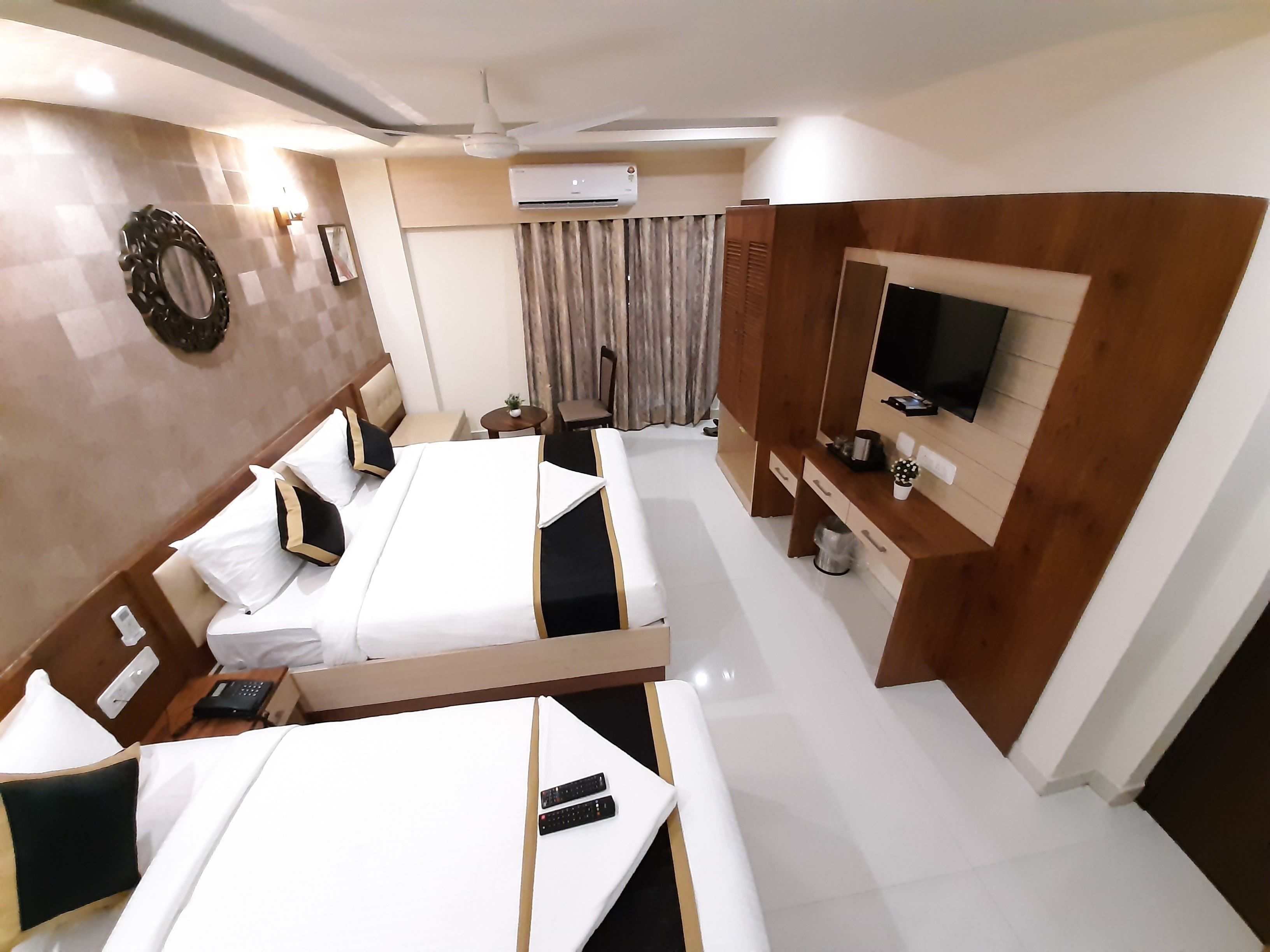 A hotel room with a large bed, a TV, a desk, and a ceiling fan.