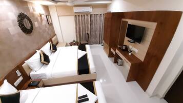 A hotel room with a large bed, a TV, a desk, and a ceiling fan.