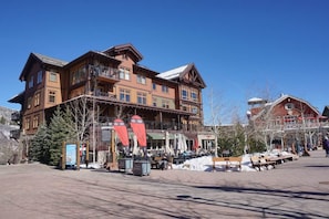 A multi-story hotel with a balcony, outdoor seating area, and snow on the ground. - Hayden Lodge  - Views Of The Slopes And Village 3 Bedroom Condo by RedAwning (Snowmass Village)