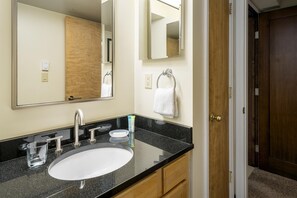Bathroom features a large oval sink, mirror, and wooden door.