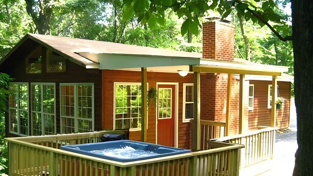 Una cabaña de madera con jacuzzi y terraza.