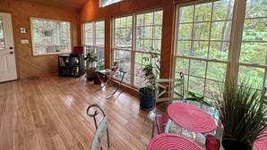 Una habitación amplia con ventanas grandes, pisos de madera y una estantería.