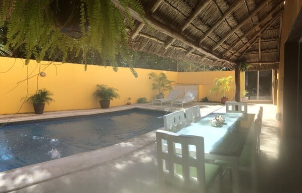Relax by the pool surrounded by lush greenery and enjoy meals at the shaded dining table.