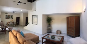 Relax in this stylish living area with a high ceiling, sofa, and coffee table, plus a staircase leading to an upper level.