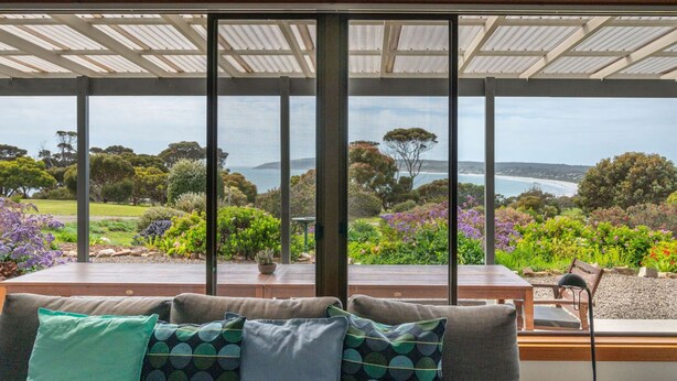 A room with a large window overlooking a garden and a view of the sea. - Emu Bay Holiday Homes (Emu Bay)