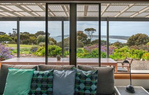 A room with a large window overlooking a garden and a view of the sea. - Emu Bay Holiday Homes (Emu Bay)