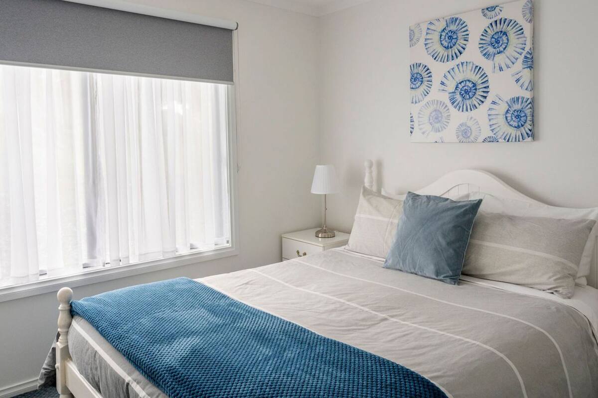 A bedroom with a bed, a nightstand, a lamp, and a window with curtains.