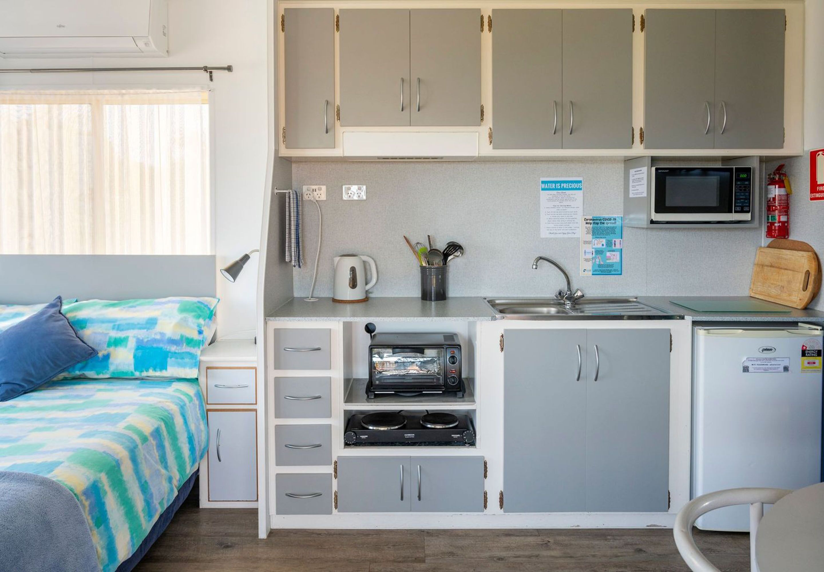 A compact kitchenette with a microwave, toaster, and sink.