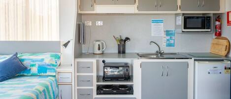 A compact kitchenette with a microwave, toaster, and sink.