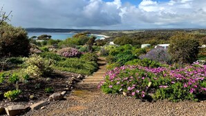 A garden with a stone pathway leading to a beach. - Emu Bay Holiday Homes (Emu Bay)