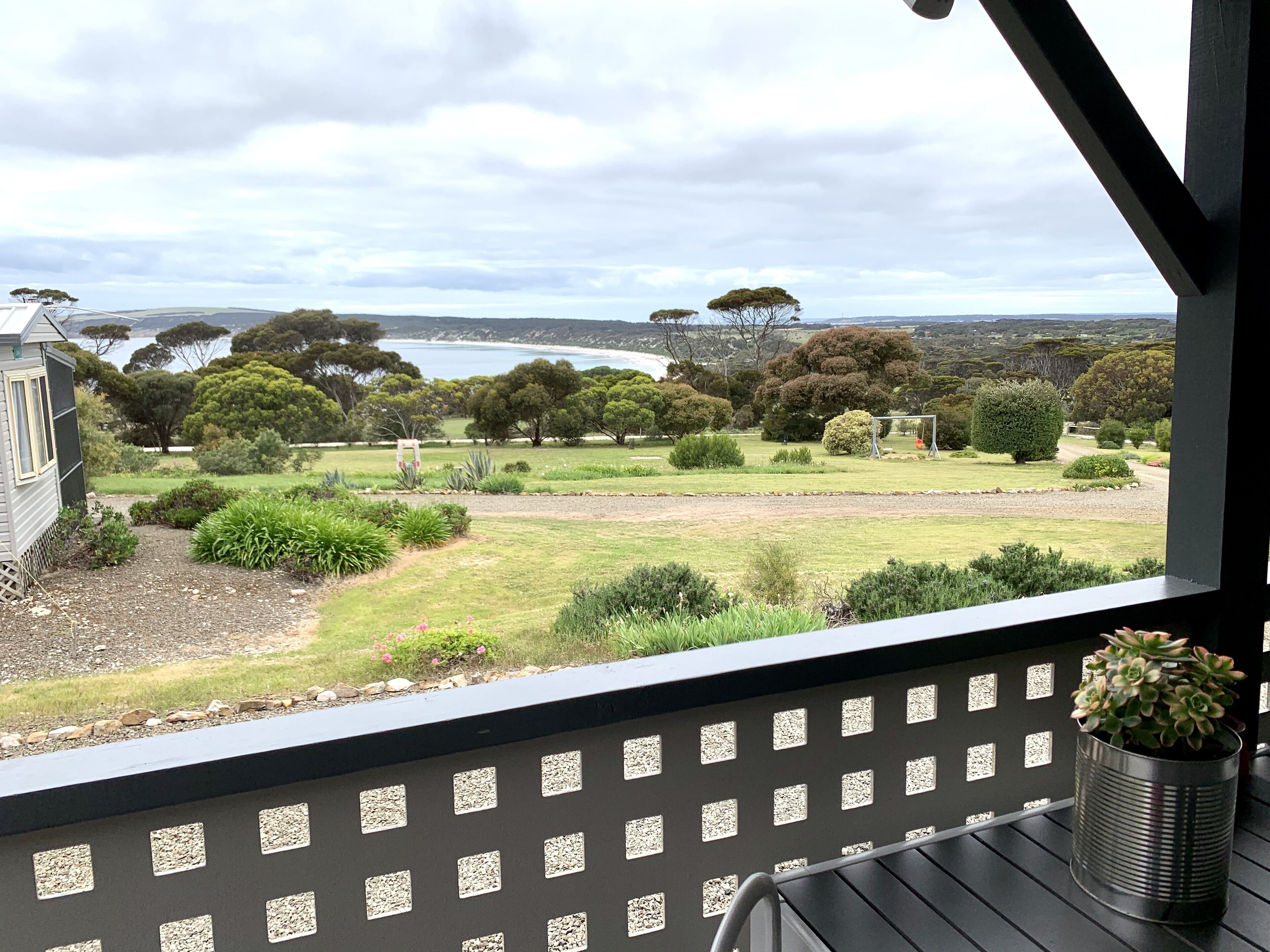 A balcony with a view of a landscaped garden and a body of water.