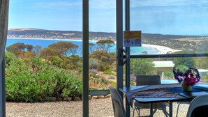 A room with a glass door leading to a scenic view of a beach and forest. - Emu Bay Holiday Homes (Emu Bay)