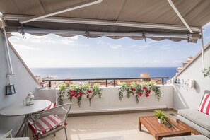 Un balcon avec vue sur la mer, une table avec des chaises et un canapé.