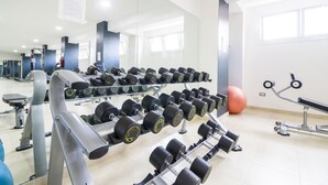Et fitnesscenter med rækker af håndvægte, træningsbolde og styrkemaskiner.