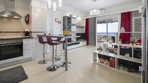 Et moderne køkken med en central ø, barstole og et spiseområde med udsigt.