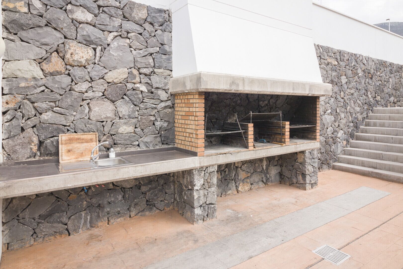Una cocina al aire libre con un muro de piedra y encimera de hormigón.