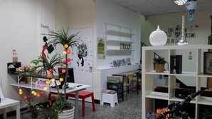 A room with a white desk, a red chair, a white shelf with books, a bicycle, and a potted plant. - Jia Mei Fa Homestay (Taitung)