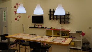 A dining area with a long table, chairs, and hanging pendant lights. - Jia Mei Fa Homestay (Taitung)