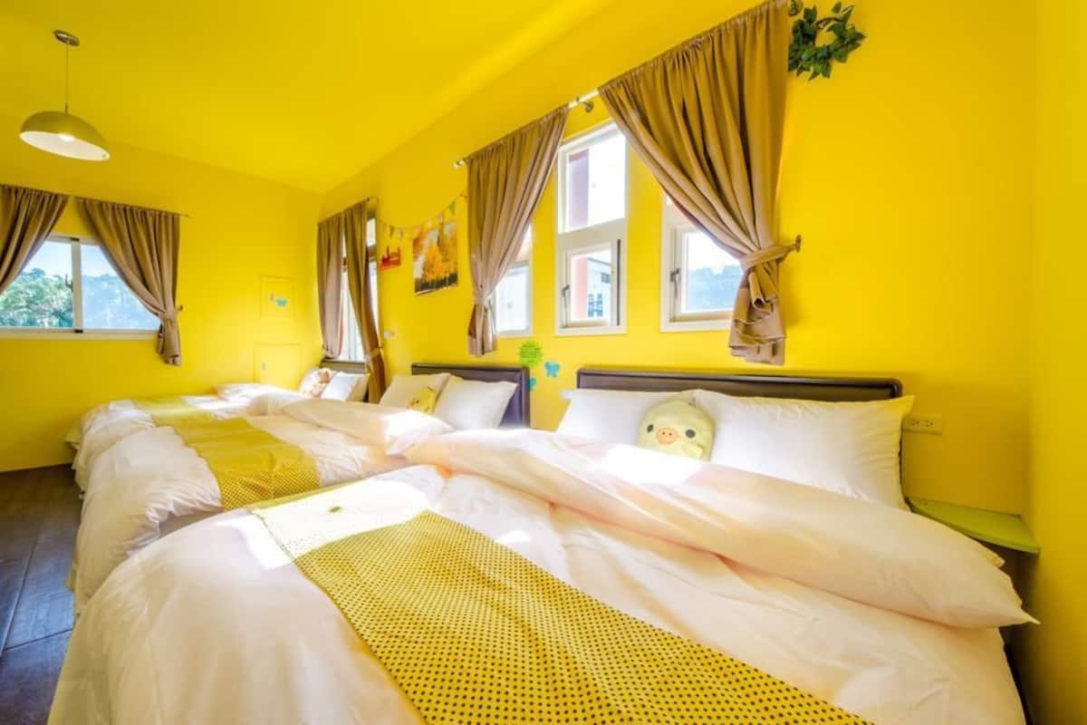 A hotel room with two beds, yellow walls, and brown curtains.
