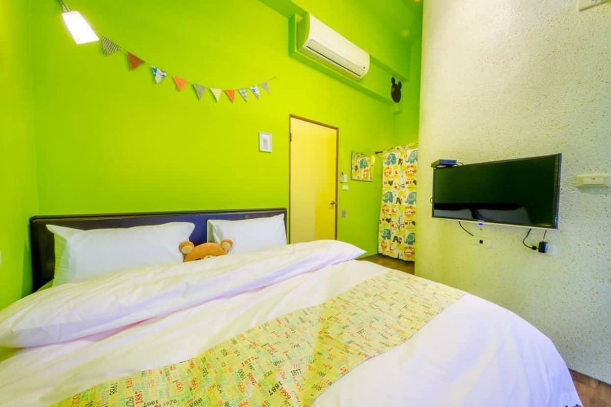 A room with a bed, a teddy bear, a TV, and a wall with a flag.
