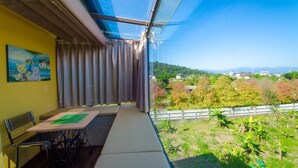 A balcony with a view of a green landscape and distant buildings. - Sunshine House (Dongshan)