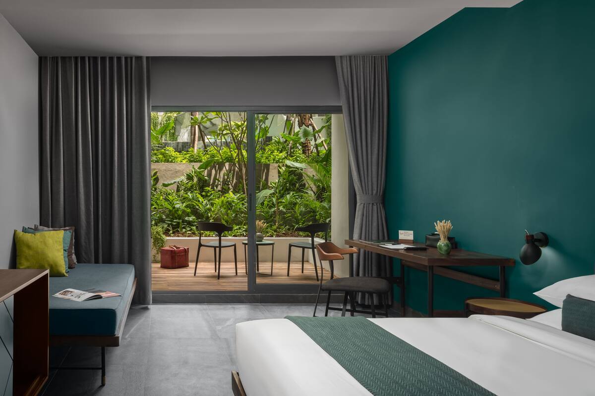 A modern hotel room with a large bed, a desk, and a seating area with chairs.