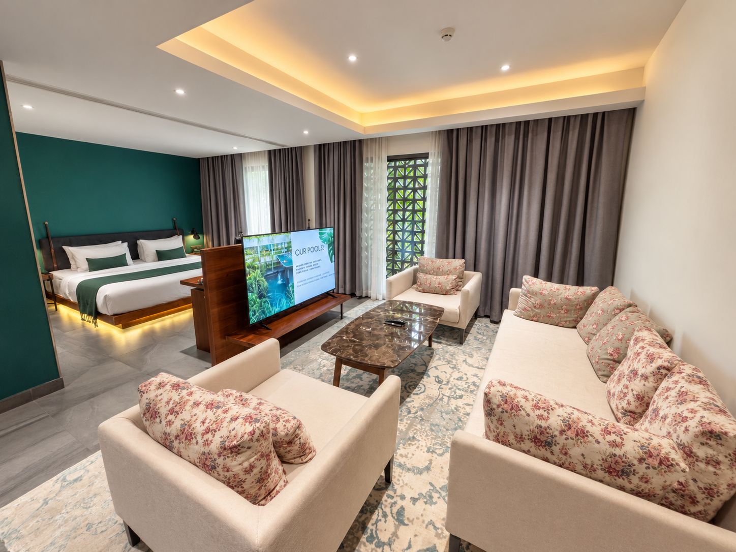 A modern hotel room with a bed, a TV, a sofa, and a coffee table.