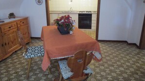 Een kleine keuken met een eettafel, stoelen en een kast.