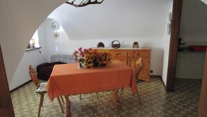 Een eetruimte met een tafel bedekt met een tafelkleed, stoelen, een houten kast en een vloer met een patroon.