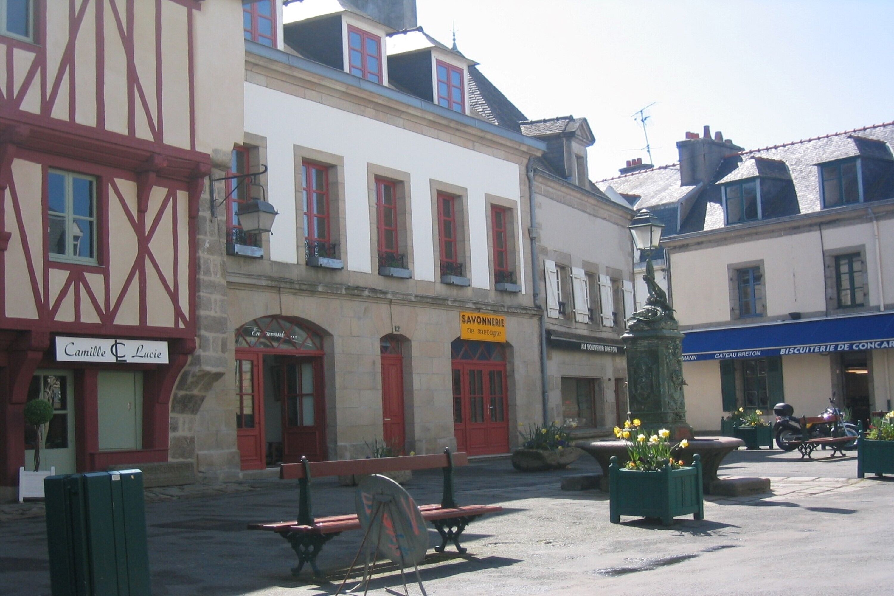Eine typische europäische Straße mit einem Café namens "Camille & Lucie" und einer Bäckerei "SAVONNERIE De Rousset".