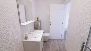 Une salle de bain moderne avec un lavabo blanc, un miroir et des toilettes.