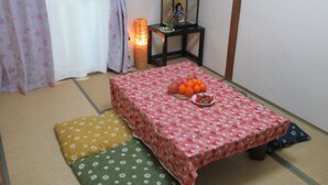 A traditional Japanese room with tatami flooring, a low table with fruit, and a small shrine. - Osaka Vacation Home (Osaka)