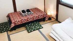 A small room with a bed, a futon, and a futon mat. - Osaka Vacation Home (Osaka)