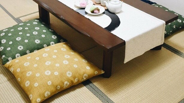 A tatami mat room with a low wooden table, a tea set, and cushions. - Osaka Vacation Home (Osaka)