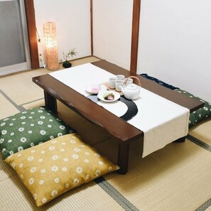 A tatami mat room with a low wooden table, a tea set, and cushions. - Osaka Vacation Home (Osaka)