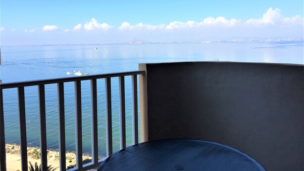 Un balcon offrant une vue sur la mer et sur les contours d’une ville lointaine.