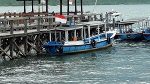 A wooden pier with a small shelter and several boats docked. - Menjangan Hostel (Pejarakan)