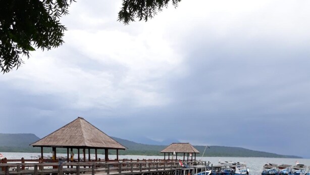 A wooden pier extending into calm waters with a thatched-roof pavilion. - Menjangan Hostel (Pejarakan)