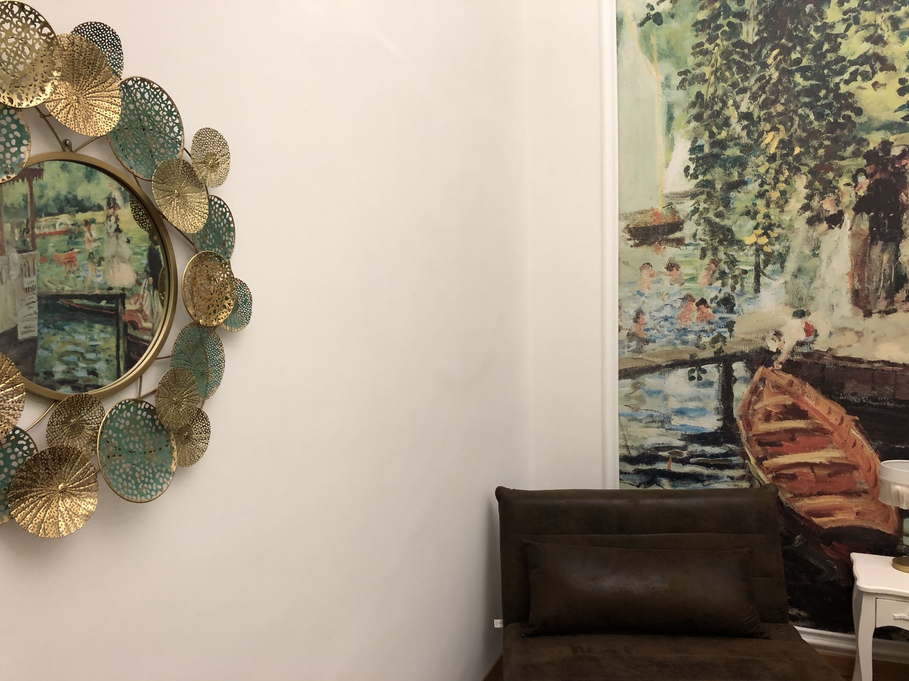 Una habitación con un espejo grande, un cuadro y un sofá marrón.