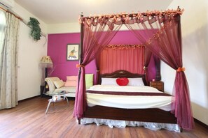 A four-poster bed with a canopy, a small bedside table, a chair, and a wall-mounted shelf with a plant. - Shuishang Ya Ju Homestay (Hualien City)