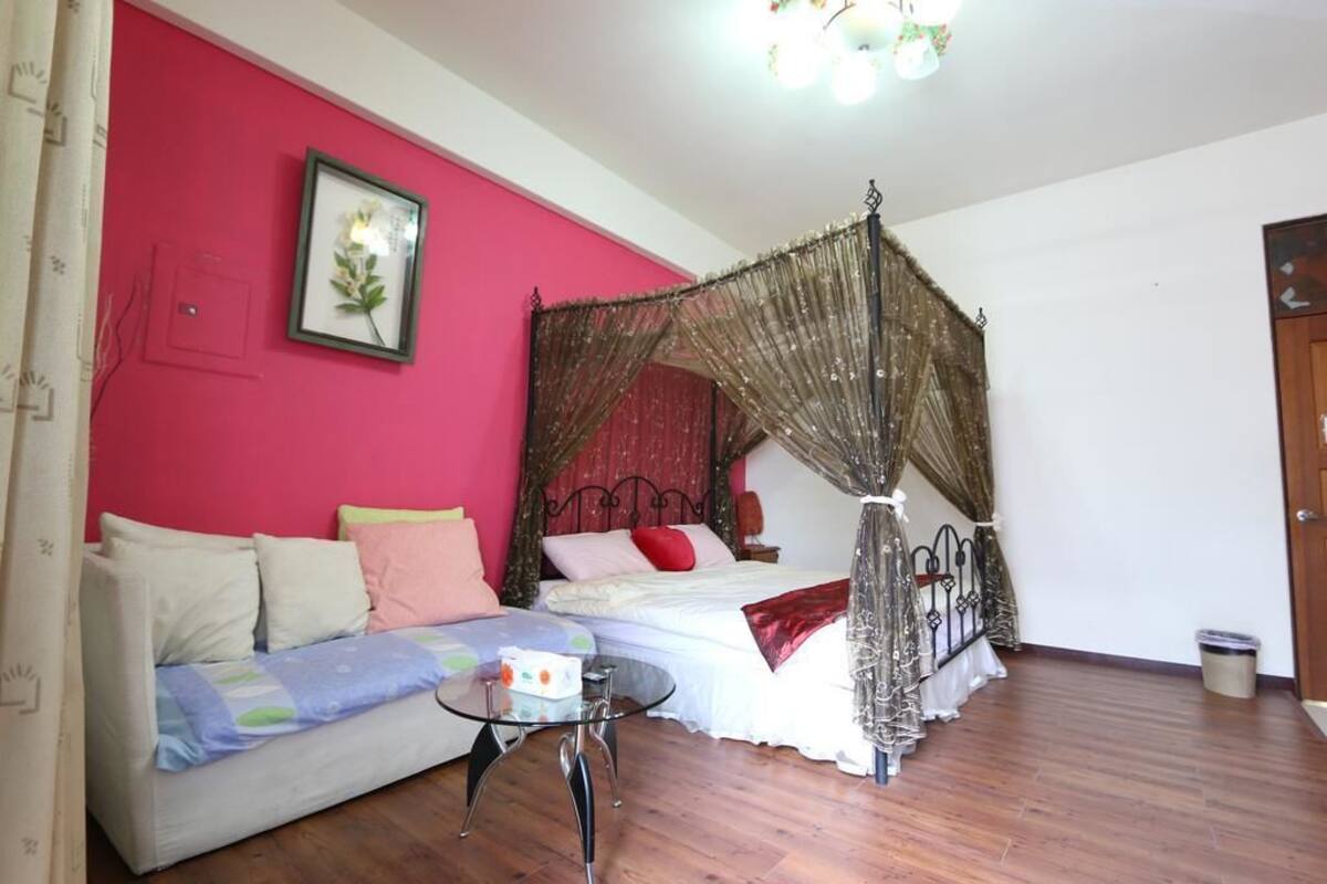 Una habitación con una cama, un sofá, una mesita y un cuadro en la pared.