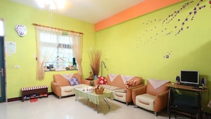A living room with a sofa set, a coffee table, a TV on a stand, and a window with curtains. - Shuishang Ya Ju Homestay (Hualien City)