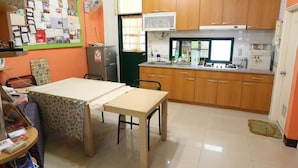 A compact kitchen with wooden cabinets, a small dining table, and a refrigerator. - Shuishang Ya Ju Homestay (Hualien City)