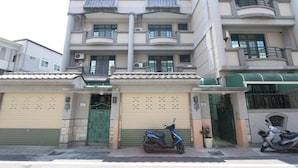 A multi-story residential building with balconies, a green gate, and a parked scooter. - Shuishang Ya Ju Homestay (Hualien City)