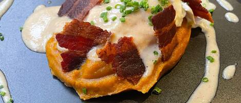 A dish with a waffle, bacon, and a creamy sauce, garnished with green onions.