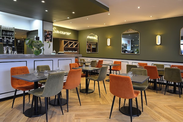 A restaurant with multiple tables and chairs, a bar area, and a large mirror on the wall.