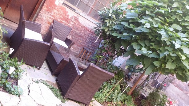 A patio area with wicker furniture and a brick wall.