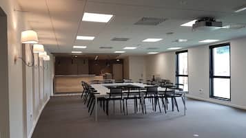 A conference room with a long table and chairs, ceiling lights, and large windows.