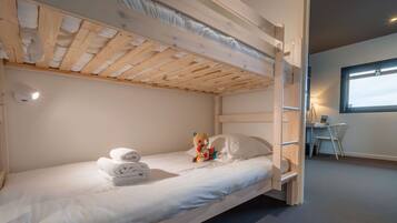Una cama litera con techo de madera, un escritorio y una silla en una habitación con ventana.